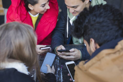 Freunde junger Erwachsener benutzen Smartphones am Cafétisch, lizenzfreies Stockfoto