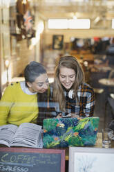 Lächelnde junge Studentinnen studieren in einem Cafe - CAIF26059