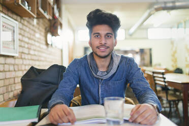 Porträt selbstbewusster junger männlicher Student, der in einem Café lernt - CAIF26086