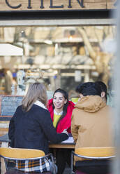 Young adult friends talking at sidewalk cafe - CAIF26093