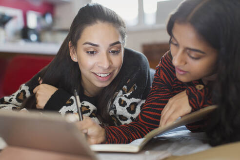 Lächelnde Teenager-Mädchen studieren mit digitalem Tablet auf dem Bett - CAIF26100