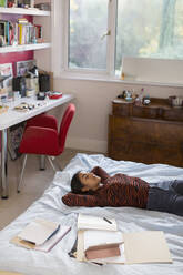 Müdes Teenager-Mädchen macht eine Pause vom Lernen und ruht sich auf dem Bett aus - CAIF26114