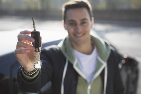 Porträt eines lächelnden, selbstbewussten jungen Mannes mit neuem Autoschlüssel - CAIF26131