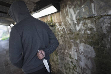 Dangerous man with knife behind back in urban tunnel - CAIF26136