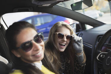 Porträt einer fröhlichen, verspielten jungen Frau mit Sonnenbrille im Auto - CAIF26139