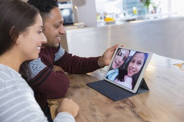 Ehepaar führt Videokonferenzen mit Töchtern über ein digitales Tablet in der Küche durch - CAIF26167