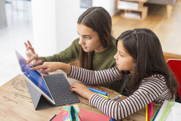 Sisters doing homework, sharing digital tablet at table - CAIF26185