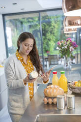 Frau mit digitalem Tablet zur Überprüfung von Lebensmitteletiketten in der Küche - CAIF26207