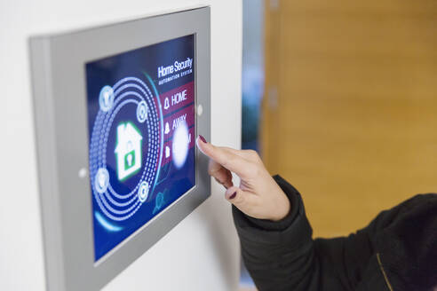 Frau stellt intelligenten Hausalarm am Touchscreen ein - CAIF26224