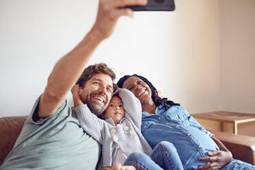 Glückliche schwangere junge Familie nimmt Selfie - CAIF26230