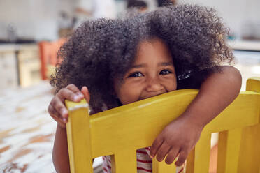 Portrait cute girl on yellow chair - CAIF26233