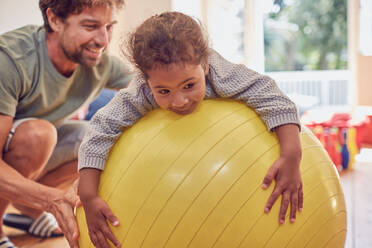 Vater und Tochter spielen mit einem Fitnessball - CAIF26235