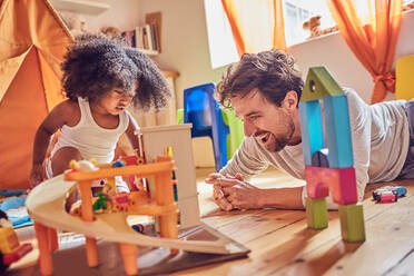 Father and toddler daughter playing with toys on floor - CAIF26244