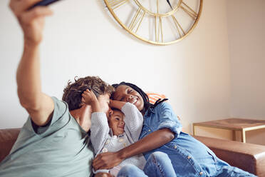 Affectionate young pregnant family taking selfie on living room sofa - CAIF26259