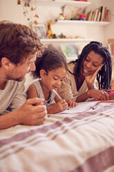 Junge Familie beim Malen auf dem Bett - CAIF26265