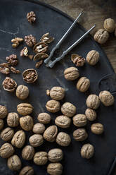 Walnuts and nutcracker lying on rustic baking sheet - ASF06604