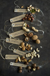 Collection of various nuts with name tags lying on rustic baking sheet - ASF06610