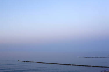 Germany, Mecklenburg-Western Pomerania, Zingst, Clear sky over groynes on Baltic Sea coast at dusk - JTF01514