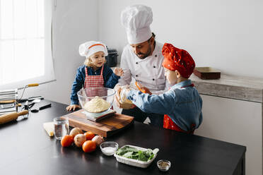 Vater mit zwei Kindern bei der Zubereitung von Teig für selbstgemachte glutenfreie Nudeln in der Küche zu Hause - JRFF04267