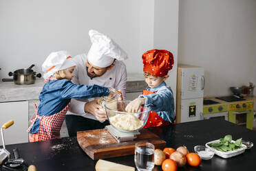 Vater mit zwei Kindern bei der Zubereitung von Teig für selbstgemachte glutenfreie Nudeln in der Küche zu Hause - JRFF04268