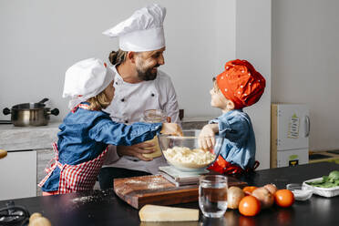 Vater mit zwei Kindern bei der Zubereitung von Teig für selbstgemachte glutenfreie Nudeln in der Küche zu Hause - JRFF04269