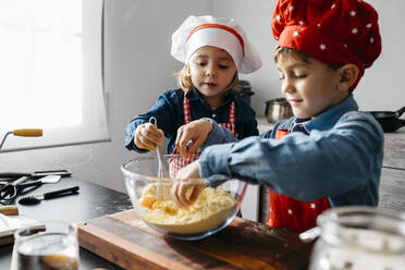 Brother and sister preparing dough in kitchen at home - JRFF04271