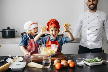Porträt von glücklichen Kindern, die mit ihrem Vater in der Küche zu Hause Teig zubereiten - JRFF04274