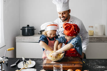 Father with two kids preparing dough in kitchen at home - JRFF04275