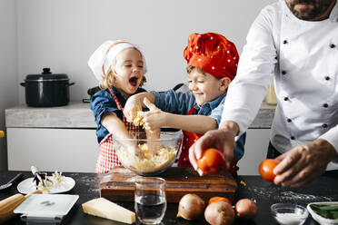 Glückliche Kinder bereiten mit ihrem Vater in der Küche zu Hause Teig vor - JRFF04276