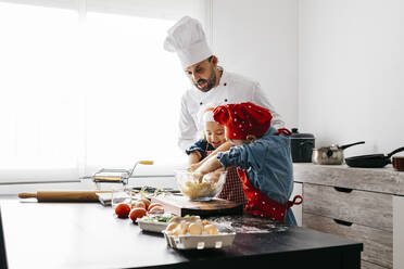 Vater mit zwei Kindern bei der Zubereitung von Teig für selbstgemachte glutenfreie Nudeln in der Küche zu Hause - JRFF04279