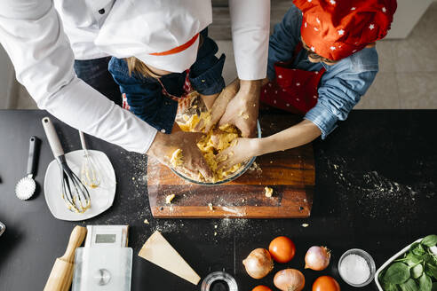 Vater mit zwei Kindern bei der Zubereitung von Teig für selbstgemachte glutenfreie Nudeln in der Küche zu Hause - JRFF04280