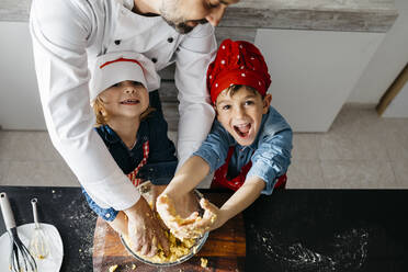 Porträt von glücklichen Kindern, die mit ihrem Vater in der Küche zu Hause Teig zubereiten - JRFF04281