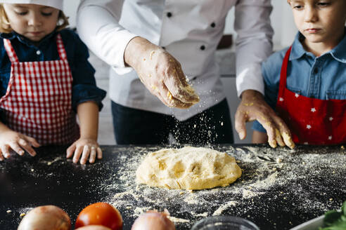 Vater mit zwei Kindern bei der Zubereitung von Teig für selbstgemachte glutenfreie Nudeln in der Küche zu Hause - JRFF04285