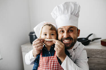 Playful father with daughter having fun while preparing homemade pasta in kitchen at home - JRFF04301