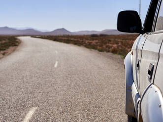 Morocco, Close-up of 4x4 car driving along empty asphalt road - VEGF01873