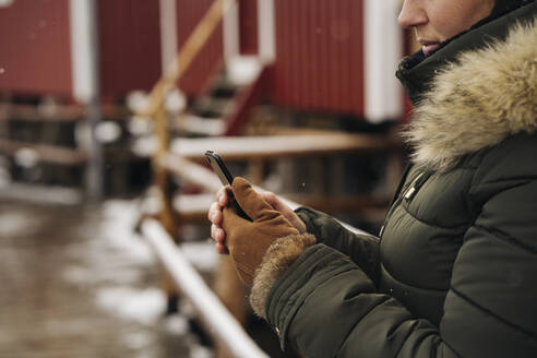 Close-up of woman using cell phone at a hut, Lofoten, Norway - MPPF00720