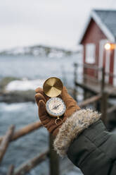 Nahaufnahme einer Hand mit Kompass an der Küste, Lofoten, Norwegen - MPPF00734