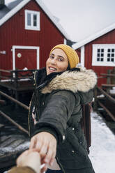Porträt eines lächelnden Touristen, der die Hand eines Mannes in einer Hütte hält, Lofoten, Norwegen - MPPF00736