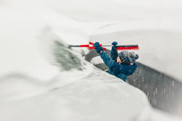 7 Jahre alter Junge nimmt den Schnee von der Windschutzscheibe während eines Schneesturms - CAVF78258