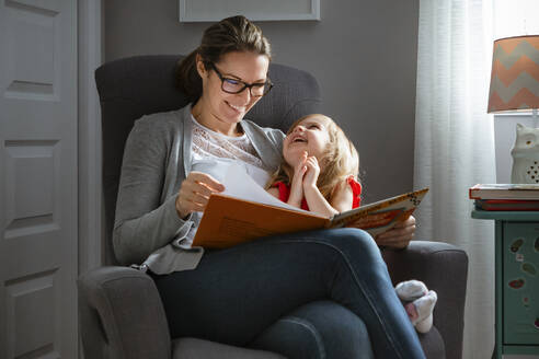 Mother and daugher enjoying reading a book on a casual afternoon - CAVF78259