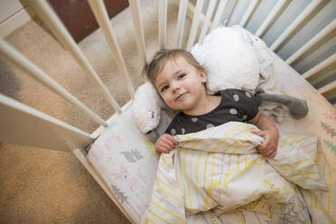 High angle view of toddler girl laying in her bed. - CAVF78283