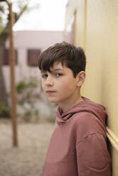 Portrait of a teenage boy leaning against wall looking camera - CAVF78355