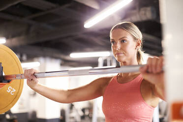 Ein Porträt einer blonden Frau, die im Fitnessstudio Gewichte hebt. - CAVF78384