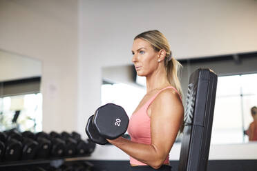 Eine Frau beim Krafttraining im Fitnessstudio. - CAVF78392