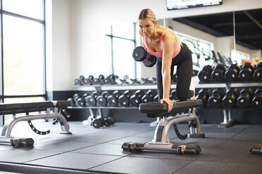 Eine Frau, die in einem Fitnessstudio mit Gewichten trainiert. - CAVF78393