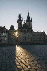 Frau, die bei Sonnenaufgang auf dem Altstädter Ring spazieren geht, in Prag, Tschechische Republik. - CAVF78551