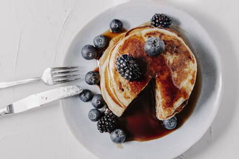 A stack of pancakes with berries and syrup - CAVF78570
