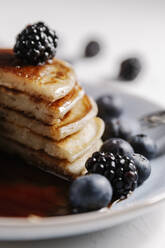 Close up of a fluffy homemade pancakes with syrup and berries - CAVF78571
