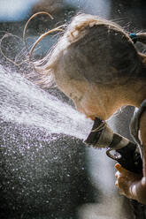 Girl drinking at the hose on a hot summer day - CAVF78690