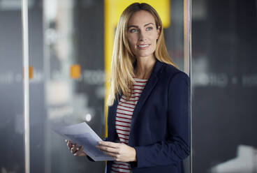 Businesswoman holding papers in office - RBF07471